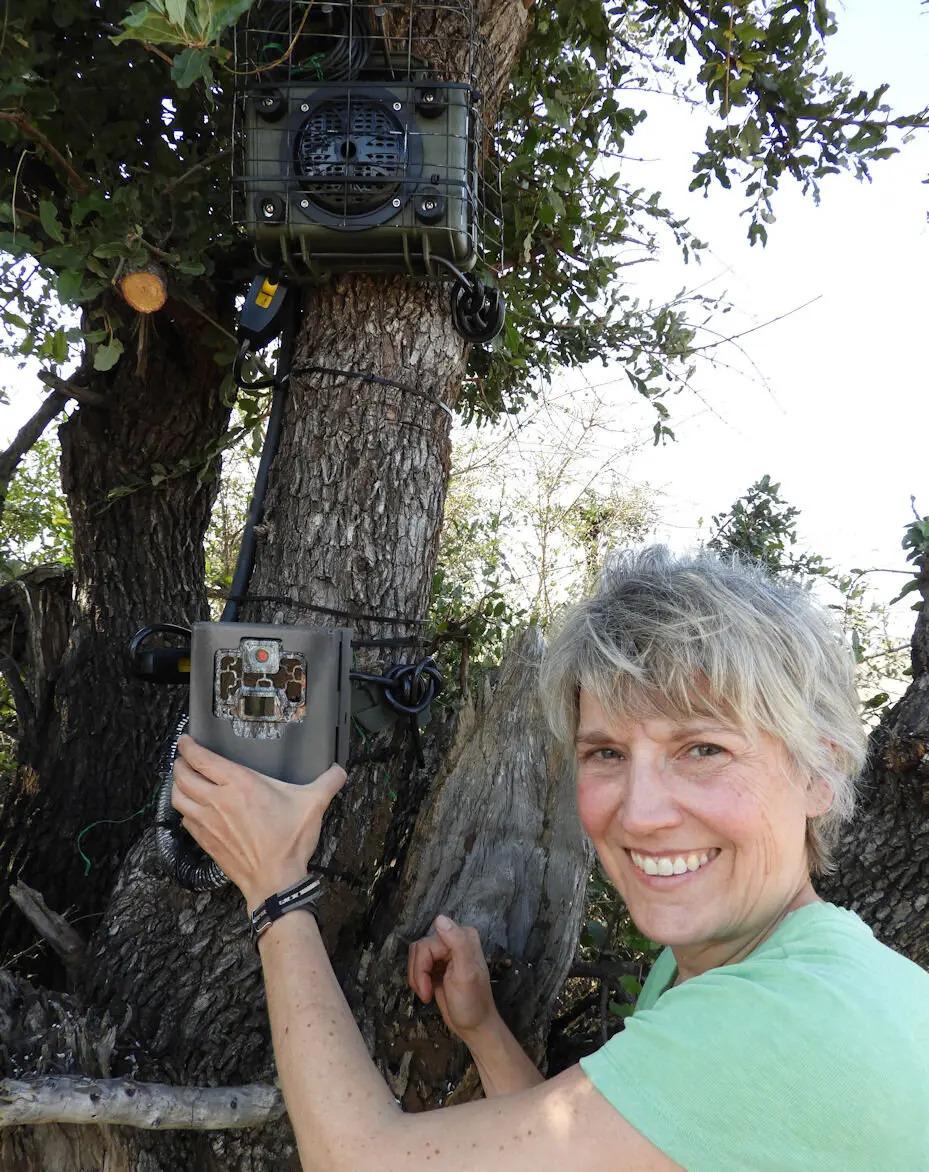 Liana Zanette with the camera trap in her left hand and the speaker playing lion noises above it